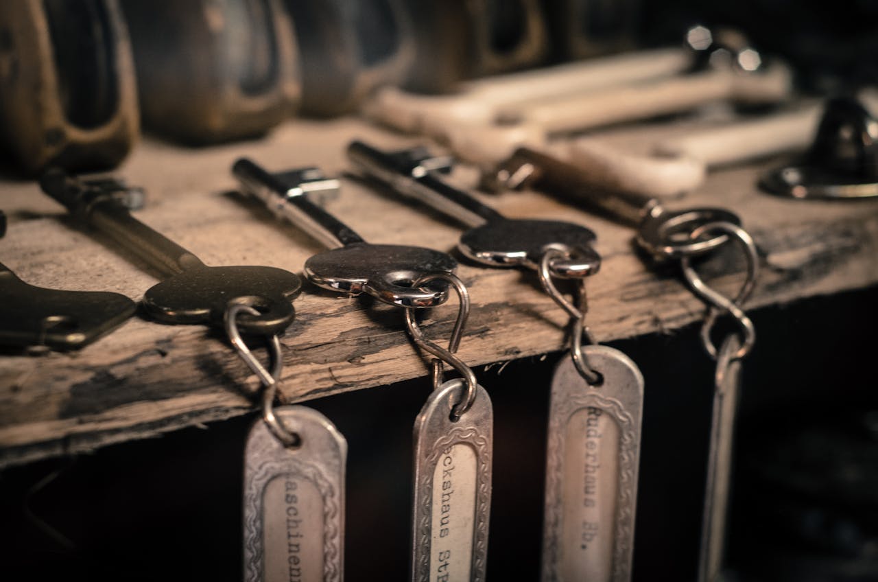 service-02 A detailed shot of antique metal keys with keychains hanging on a rustic wooden surface.