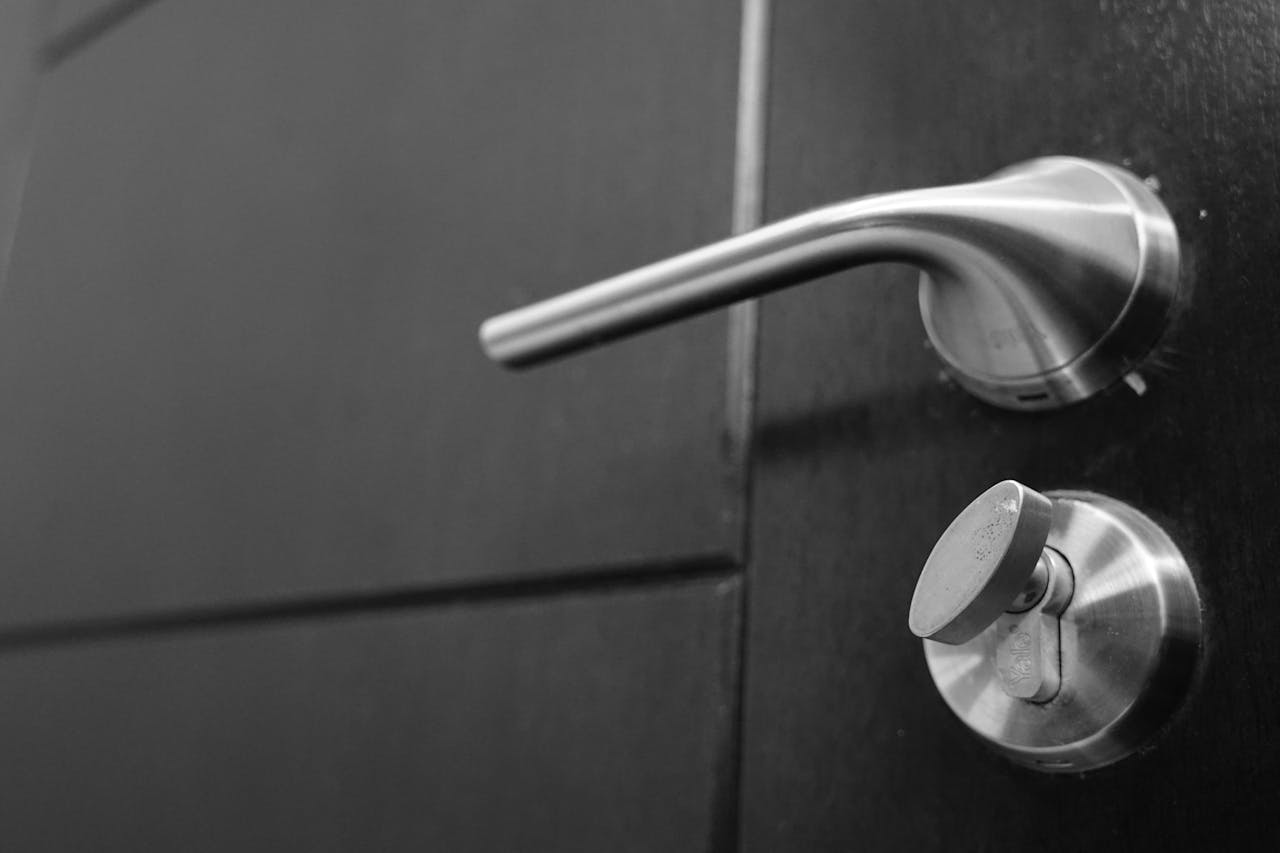 The Art of Drawing Readers In: Your attractive post title goes here Black and white photo capturing a sleek stainless steel door handle with a focus on style and security.