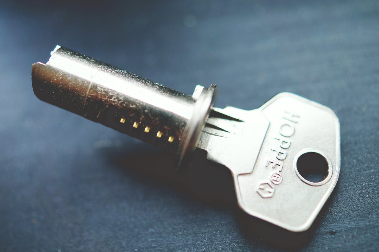 service-01 Detailed close-up image of a metallic key with lock cylinder on a dark surface, highlighting intricate details.