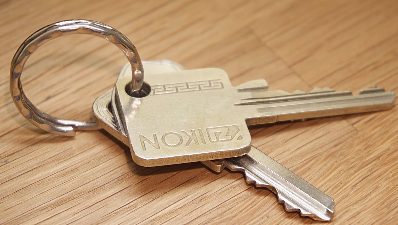 our-stories A set of metal house keys on a wooden surface, ideal for real estate themes.